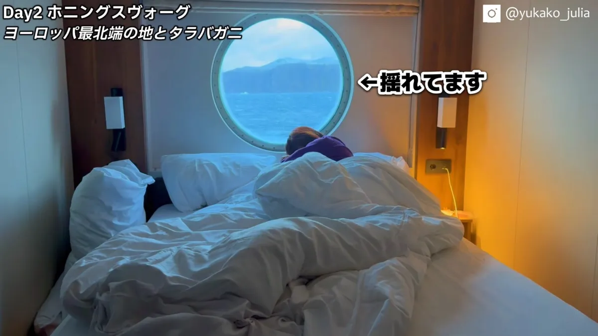 外洋で揺れた日の客室。丸窓の外に荒れた海